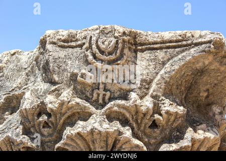 La menorah intemprata su questa antica capitale a pilastri presso la Sinagoga Bianca di Cafarnao, Israele, mostra l'erosione del tempo. Foto Stock