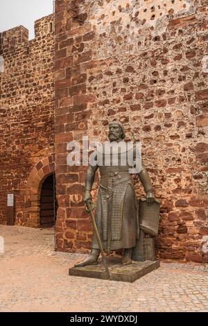 La statua in bronzo di Alfonso III è di guardia all'ingresso del castello di Silves in Portogallo. Foto Stock