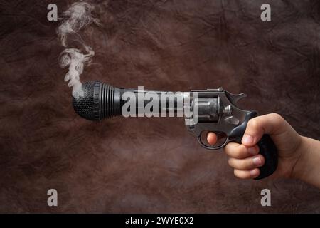 Revolver con cilindro microfono nella mano di un bambino e fumare, su marrone Foto Stock