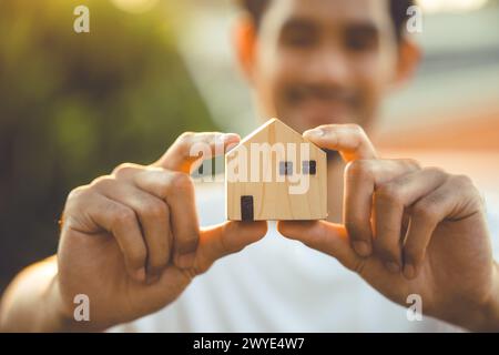 persone che tengono a mano il modello di casa in legno in miniatura per l'edilizia bancaria mutuo affitto immobiliare affitto casa concetto di famiglia Foto Stock