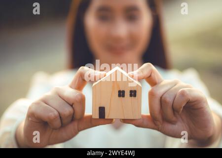 persone che tengono a mano il modello di casa in legno in miniatura per l'edilizia bancaria mutuo affitto immobiliare affitto casa concetto di famiglia Foto Stock