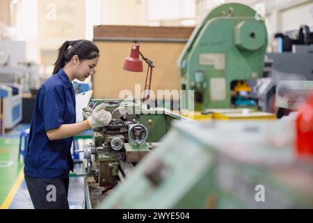 Le lavoratrici asiatiche lavorano nell'industria pesante con la fresatrice per tornio CNC in fabbrica di prodotti in acciaio Foto Stock