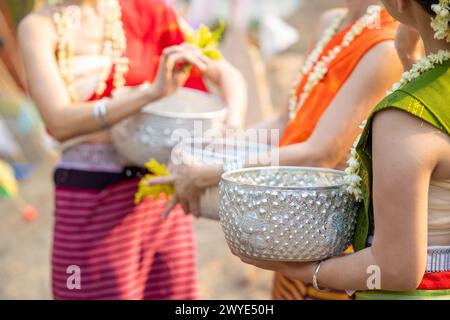 Festival di Songkran. Primo piano dei thailandesi in abiti tradizionali a Songkran, con la mano che tiene una ciotola d'argento artigianale che trasporta il tog che spruzza acqua Foto Stock