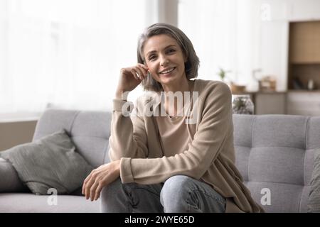 Donna matura positiva che posa per la macchina fotografica a casa Foto Stock