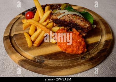 Polpette Cevapcici in stile balcanico con salsa Ajvar, cipolle, prezzemolo, patatine fritte e pepe alla griglia Foto Stock