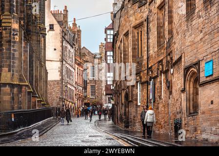 Edimburgo, Scozia - 22 gennaio 2024: La stretta strada acciottolata di Castlehill, che conduce tra vecchi edifici verso il Castello di Edimburgo Foto Stock