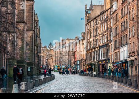Edimburgo, Scozia - 22 gennaio 2024: La strada acciottolata tra i vecchi edifici lungo il Royal Mile nella città vecchia di Edimburgo Foto Stock