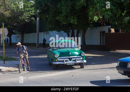 Auto d'epoca americana guidata da un uomo in bicicletta a l'Avana, Cuba Foto Stock