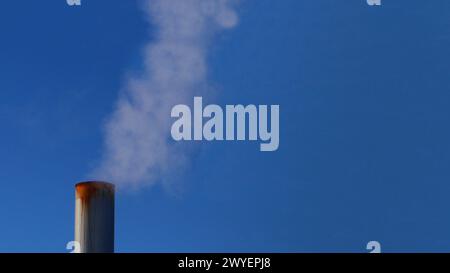 Concetto di emissioni di carbonio. Camino di Rusty. sullo sfondo di un cielo azzurro. Il fumo di fabbrica causa inquinamento nell'aria. Fumare il camino contro Foto Stock