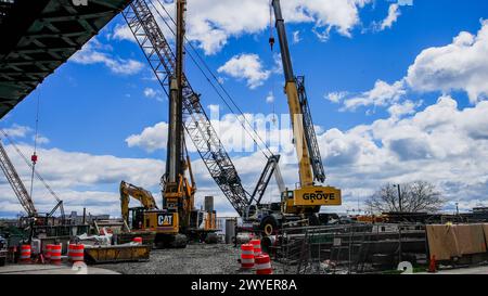 NORWALK, CT, USA - 5 APRILE 2023: Gru da costruzione che opera sotto il cielo blu nel cantiere urbano durante il giorno vicino al fiume Norwalk Foto Stock