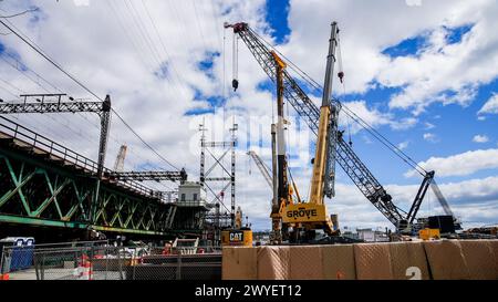 NORWALK, CT, USA - 5 APRILE 2023: Gru da costruzione che opera sotto il cielo blu nel cantiere urbano durante il giorno vicino al fiume Norwalk Foto Stock