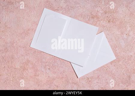 Busta di carta, invito di nozze con spazio per la copia del testo su sfondo rosa. Concetto di saluto per le festività, posizione orizzontale, vista dall'alto Foto Stock