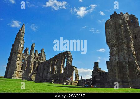 I turisti si godevano il sole estivo a Whitby Abbey. Whitby Abbey era un'abbazia benedettina che fu ridotta al suo stato attuale da Enrico VIII i Foto Stock