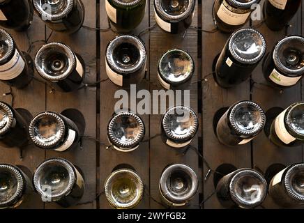 File di bottiglie di vino alsaziano sul fondo di una cantina locale a Riquewihr, in Alsazia, Francia. Foto Stock