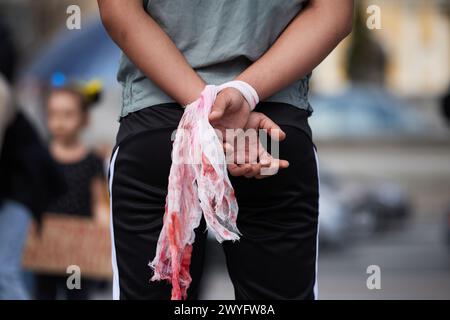 Attivista ucraino con le mani legate dipinte con il sangue alla protesta pubblica contro l'aggressione russa. Kiev - 6 aprile 2024 Foto Stock