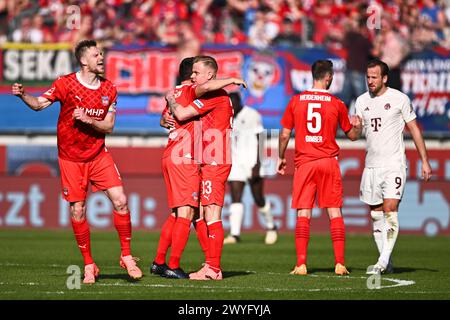 Heidenheim, Germania. 6 aprile 2024. Calcio: Bundesliga, 1. FC Heidenheim - Bayern Monaco, Matchday 28, Voith-Arena. Harry Kane (r) di Monaco si congratula con Benedikt Gimber di Heidenheim dopo la partita, mentre i giocatori di Heidenheim celebrano la vittoria. NOTA IMPORTANTE: In conformità con i regolamenti della DFL German Football League e della DFB German Football Association, è vietato sfruttare o fare sfruttare fotografie scattate nello stadio e/o della partita sotto forma di immagini sequenziali e/o serie di foto video. Credito: Tom Weller/dpa/Alamy Live News Foto Stock