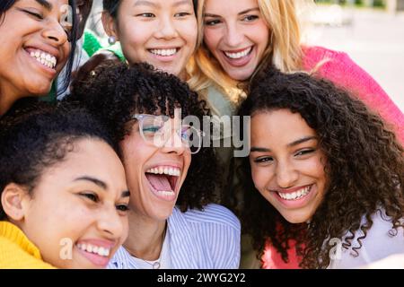 Vista ravvicinata di un gruppo felice di ragazze diverse che ridono insieme all'aperto. Foto Stock