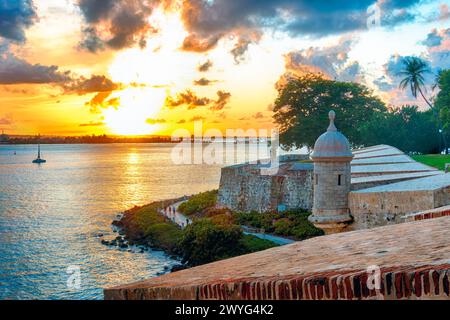 Vista ad angolo alto della Baia di San Juan con le mura della città di San Juan e il Paseo del Morro al tramonto, Porto Rico Foto Stock