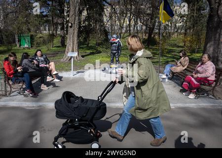 5 aprile 2024, Kiev, Ucraina: Una donna vista spingere un passeggino nel parco accanto al monumento raffigurante il personaggio dei cartoni animati Stitch del cartone animato "Lilo e Stitch" in uniforme militare, eretto in onore del cecchino ucraino Ihor Voevodin con il soprannome Stitch, che è morto in battaglie con l'esercito russo, è visto in un parco nel centro di Kiev. Lo studente ucraino Ihor Voevodin si offrì volontario per il fronte dopo l'invasione russa e servì come cecchino nel reggimento Azov. Ihor Voevodin è stato ucciso nell'agosto 2023 durante una missione di combattimento nella regione di Luhansk, in Ucraina. (Immagine di credito: © Oleksii Chumachenko Foto Stock