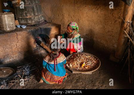 La madre e la figlia di Hmong floreale preparano il mais nella fornace nella loro casa sulle montagne nel nord del Vietnam nel sud-est asiatico Foto Stock