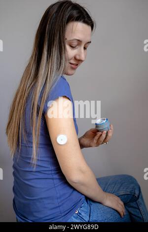 Ragazza che applica il cerotto di monitoraggio del glucosio flash sul braccio Foto Stock