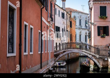 Venezia, Italia - 14 agosto 2023: Canale panoramico con ponte e vecchi edifici con piante in vaso a Venezia, Italia Foto Stock