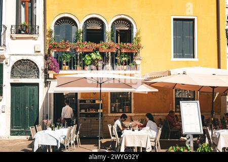 Venezia, Italia - 14 agosto 2023: Tavoli e sedie in una piccola piazza a Venezia Foto Stock