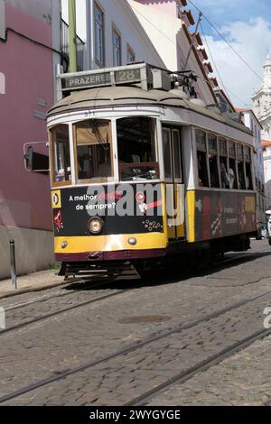 Il famoso tram giallo attraversa i quartieri più antichi, Lisbona, Portogallo. Il tram giallo è molto popolare tra i turisti. Foto Stock