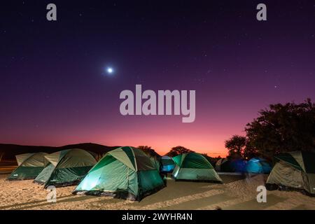 Una luna piena illuminò questa scena di prima mattina di un gruppo di tende in un campeggio nel sud della Namibia. Foto Stock