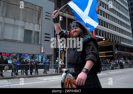 New York, Stati Uniti. 6 aprile 2024. Un partecipante alla parata marciò mentre sventolava la bandiera scozzese alla 26a parata annuale del Tartan Day di New York City sulla Sixth Avenue. La parata annuale che commemora la cultura scozzese, attira bagpiper, ballerini delle Highland, organizzazioni scozzesi-americane e festeggiamenti a Midtown Manhattan, New York City. Nel 1998, il Senato degli Stati Uniti istituì il 6 aprile come National Tartan Day "per riconoscere gli eccezionali risultati e contributi degli scozzesi americani agli Stati Uniti". Credito: SOPA Images Limited/Alamy Live News Foto Stock