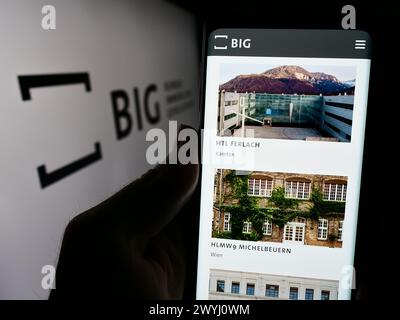 Persona che detiene un cellulare con pagina web della società Bundesimmobiliengesellschaft m.b.H. (GRANDE) davanti al logo. Messa a fuoco al centro del display del telefono. Foto Stock