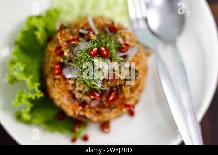 Piatti thailandesi, riso al gelsomino fritto con sgombro di pesce in scatola in salsa di pomodoro, condito con peperoncino rosso, cipolla rossa, lattuga e foglie di lime kaffir. Foto Stock