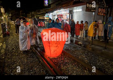 Turisti e curiosi partecipano all'uscita serale di lanterne per augurare il nuovo anno sui binari del treno di Shifen Foto Stock