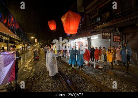 Turisti e curiosi partecipano all'uscita serale di lanterne per augurare il nuovo anno sui binari del treno di Shifen Foto Stock