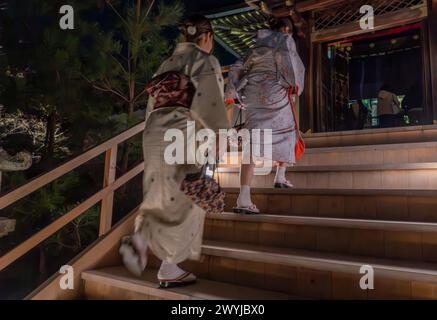Donne in abito tradizionale che visitano l'illuminazione notturna nei templi durante la stagione sakura dei ciliegi in fiore e i festival a Kyoto, in Giappone Foto Stock