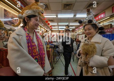 Una coppia felice posa con peluche di tigre durante un evento festivo in una strada decorata durante il capodanno cinese. Foto Stock