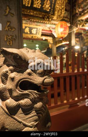 Cattura ravvicinata dettagliata di una tradizionale scultura di drago asiatico in un tempio con illuminazione soffusa Foto Stock