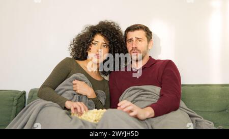 Coppia che guarda film terrore mangiando popcorn a casa Foto Stock
