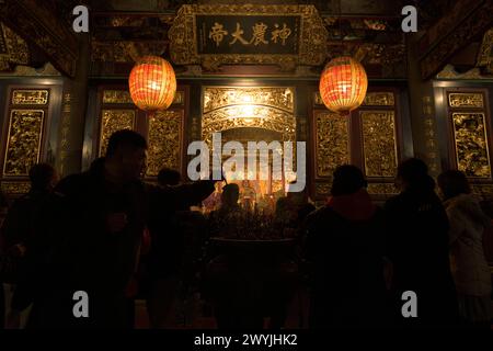 Devoti che pregano nel tempio Baoan pieno di fumo di incenso, durante una cerimonia di Capodanno cinese Foto Stock