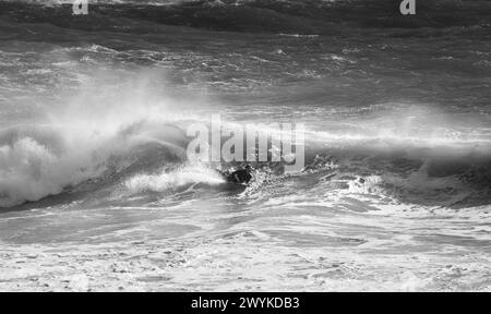 Wave board o body board navigando in enormi breakers a Kynance Cove, Cornovaglia. Affrontare le onde. Foto Stock