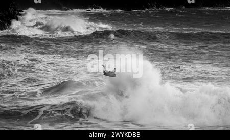 Wave board o body board navigando in enormi breakers a Kynance Cove, Cornovaglia. Una mossa acrobatica. Affrontare le onde. Foto Stock