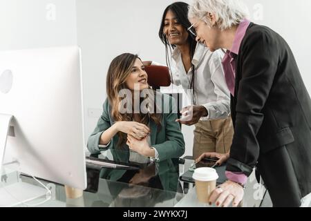 Donne d'affari sul lavoro - tre donne professionali multirazziali impegnate in una discussione di riunione collaborativa in un ufficio moderno, che rappresenta emp femminile Foto Stock