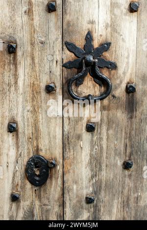 Primo piano di una porta molto vecchia con battente in ferro battuto e buco in disuso. Foto Stock