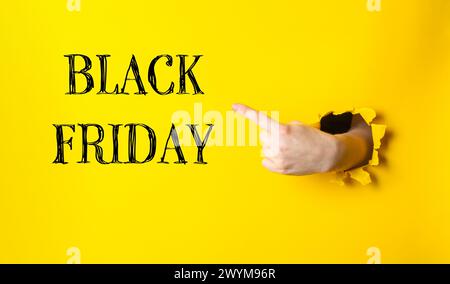 Una mano che indica uno sfondo giallo con le parole Black Friday scritte in nero. Concetto di eccitazione e anticipazione per le prossime vacanze Foto Stock