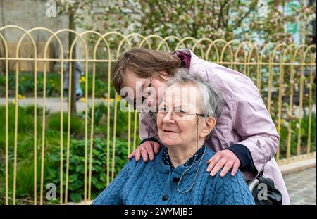 Figlia felice con la sindrome di Down che abbraccia la sua madre di 85 anni su una sedia a rotelle, Tienen, Belgio, modello rilasciato Foto Stock