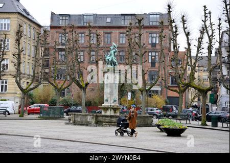 Una donna spinge un passeggino in una piazza con una statua storica nel quartiere Frederiksberg di Copenhapen, Danimarca, Europa Foto Stock