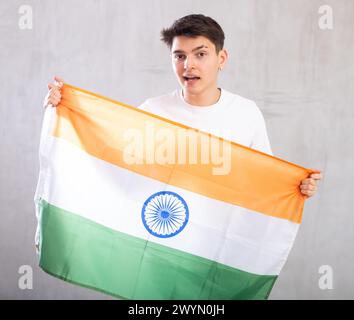 Lo spettatore maschio attivo e pieno di energia tiene in mano la bandiera nazionale dell'India e canta slogan popolare. Foto Stock