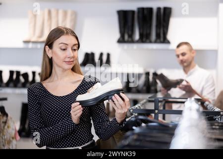 L'acquirente femminile guarda le calzature della nuova collezione e acquista un nuovo paio di mocassini Foto Stock