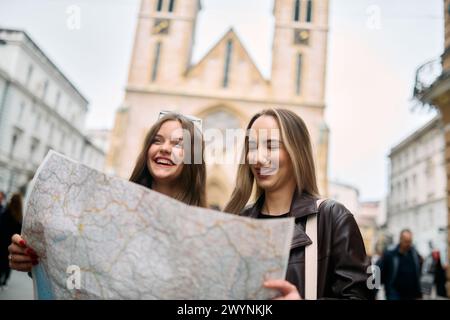 Due donne turisti si impegnano in una vivace discussione, circondate dai loro bagagli, mentre pianificano il loro viaggio turistico attraverso le vivaci strade della città Foto Stock