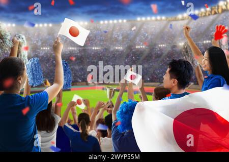 Tifoso di calcio giapponese nello stadio. Tifosi giapponesi sul campo da calcio che guardano le partite di squadra. Gruppo di tifosi con bandiera e maglia nazionale che tira Foto Stock